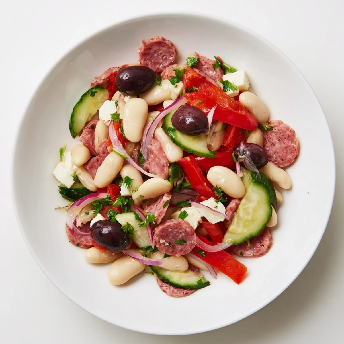 A bowl of colorful Italian Antipasto Bean Salad featuring salami, provolone, and juicy halved cherry tomatoes.