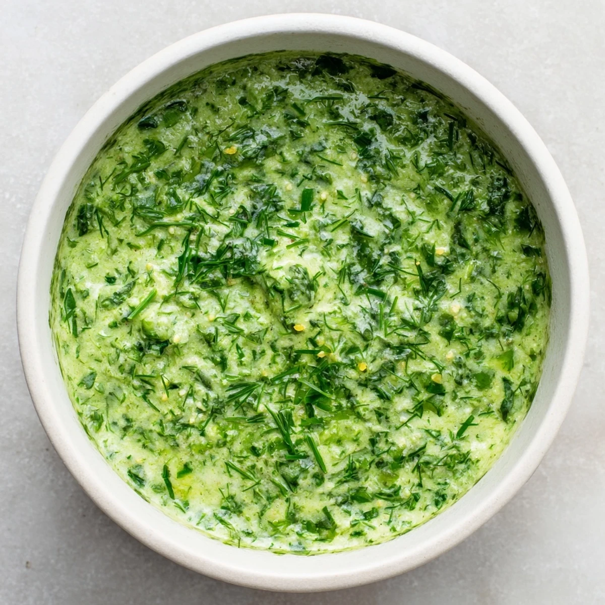 Creamy, vibrant Green Goddess Dip ready to serve with colorful vegetables and crisp pita chips.