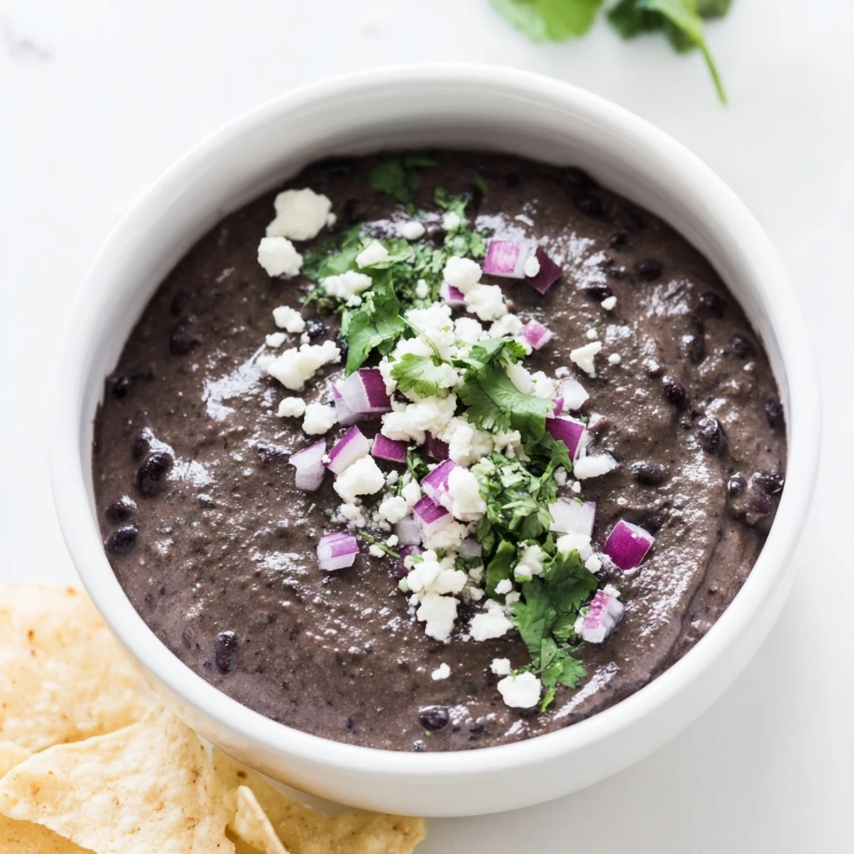 Smooth Spicy Black Bean Dip with a drizzle of olive oil and lime, served with colorful veggie sticks for dipping.