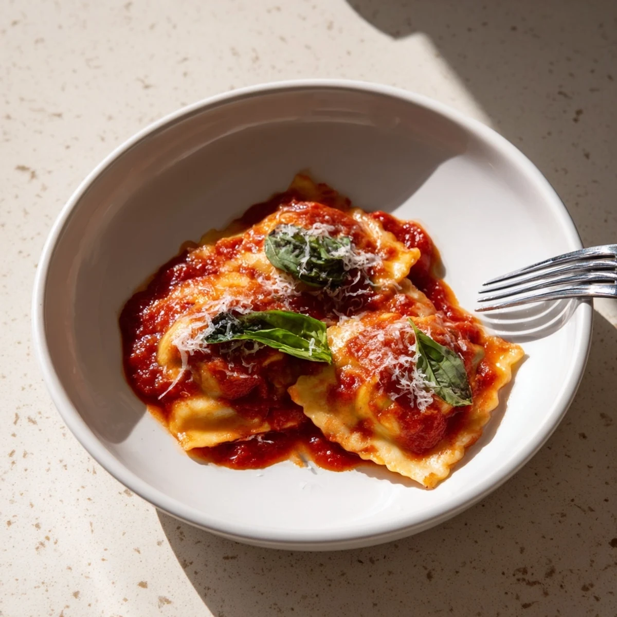 Freshly made spinach ricotta ravioli simmering in a rich marinara sauce, topped with basil and Parmesan cheese.