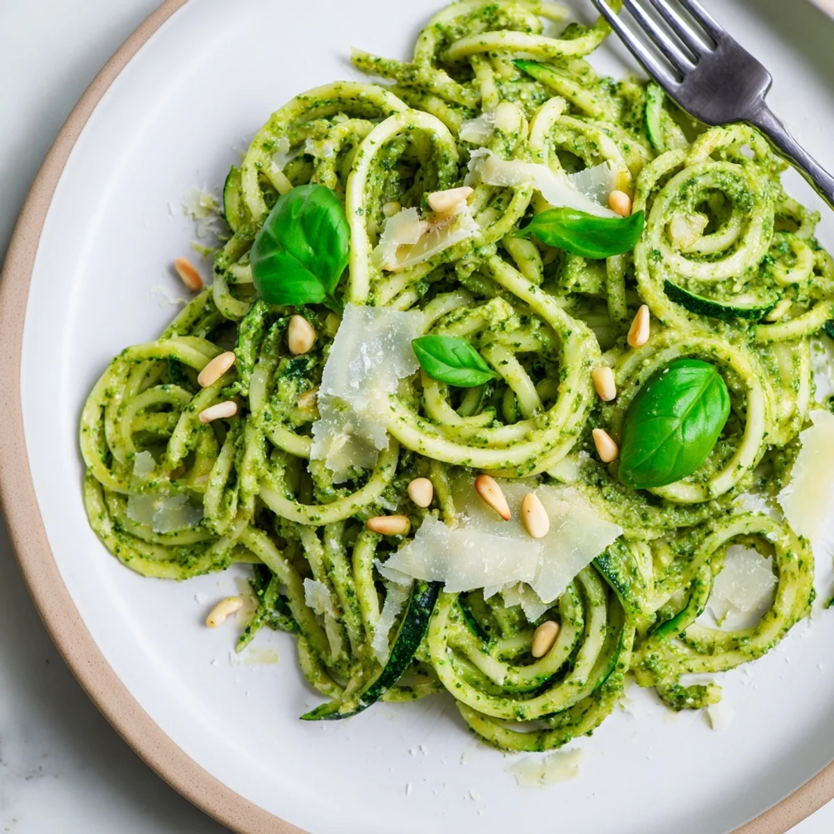 Low-carb zucchini noodles with pesto served on a white plate, ready for a quick and healthy weeknight dinner.