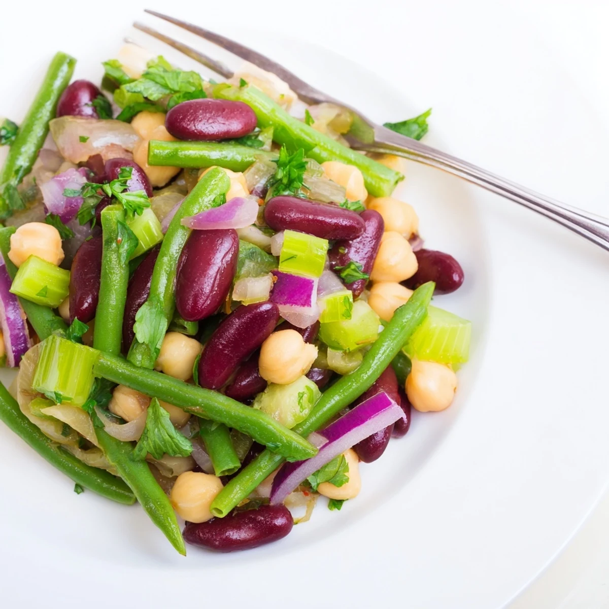 A chilled bowl of Three-Bean Salad with crisp green beans, red kidney beans, and chickpeas in a glistening vinaigrette, ready for a picnic.