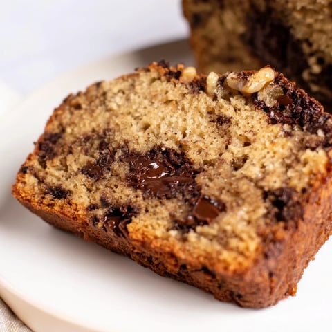 Fresh from the oven, a slice of chocolate chip banana bread offers a warm, comforting aroma.