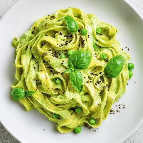 Creamy Green Pea Alfredo served on a white plate, garnished with fresh basil and extra Parmesan.  
