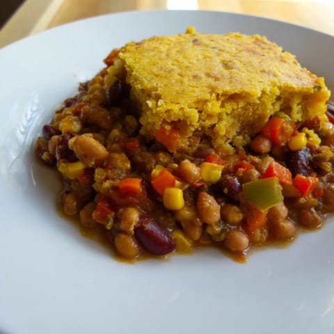 A steaming bowl of Rustic Wheat-Warm Chili with its cornbread lid, perfect for a chilly night.