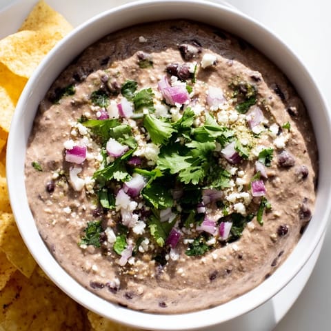 Vibrant bowl of Spicy Black Bean Dip garnished with crumbled cotija and fresh cilantro, perfect for a taco night appetizer.  
