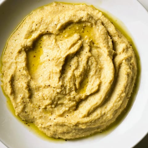 A food processor blends chickpeas and aromatic spices into a smooth Chickpea Curry Paste, ready to be served with warm pita or naan bread.