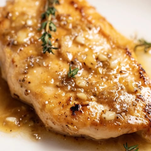 Golden-brown Honey Dijon Chicken Skillet simmering in a glossy, aromatic sauce with fresh thyme and rosemary.  