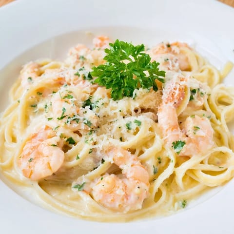 Steaming Creamy Garlic Shrimp Pasta twirls on a fork with tender shrimp in rich, garlicky cream sauce.