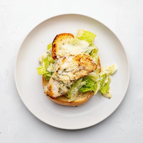 Grilled chicken cutlets rest on toasted brioche buns topped with crisp romaine and creamy Caesar dressing.