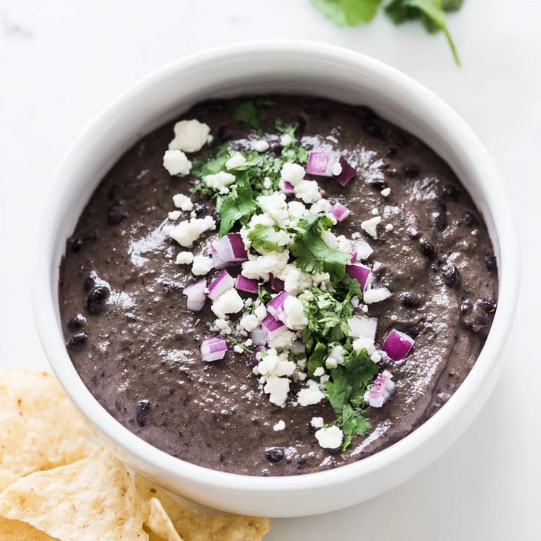 Smooth Spicy Black Bean Dip with a drizzle of olive oil and lime, served with colorful veggie sticks for dipping.