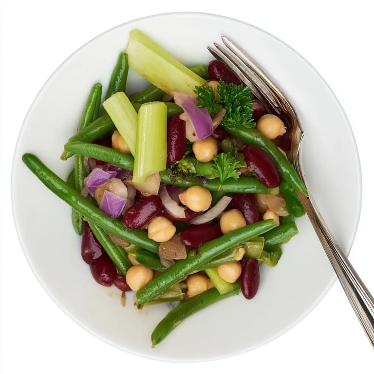 Three-Bean Salad garnished with fresh parsley, diced red onion, and celery, mixed in a tangy apple cider vinegar dressing for a healthy side.