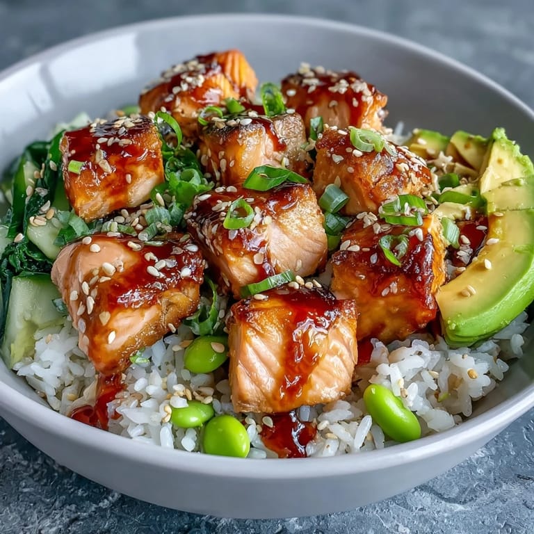 A deconstructed Salmon Rice Bowl showcases crisp cucumber, green onions, and sesame seeds for a fresh, crunchy finish.