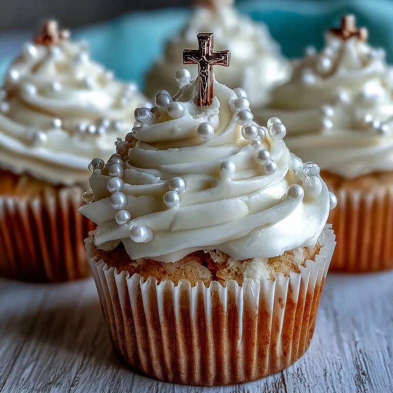 Soft vanilla mini cupcakes topped with creamy buttercream and delicate fondant rosary toppers, ideal for religious gatherings.