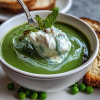 Spring pea soup with whipped ricotta and mint looks vibrantly green and creamy.
